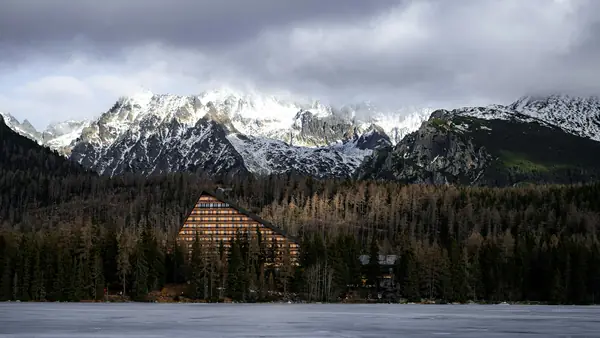 Horský hotel pri zamrznutom jazere pod zasneženými štítmi